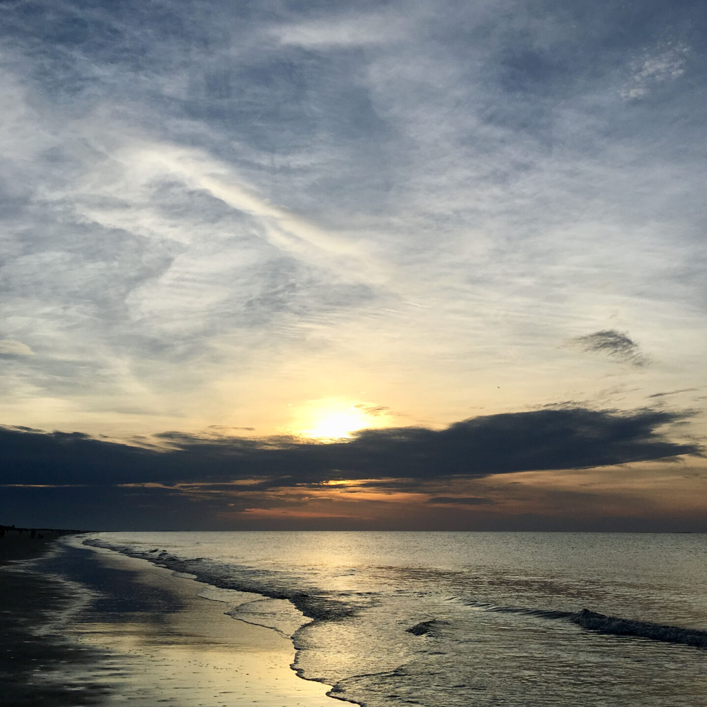 A sunset over the ocean with clouds in the sky.